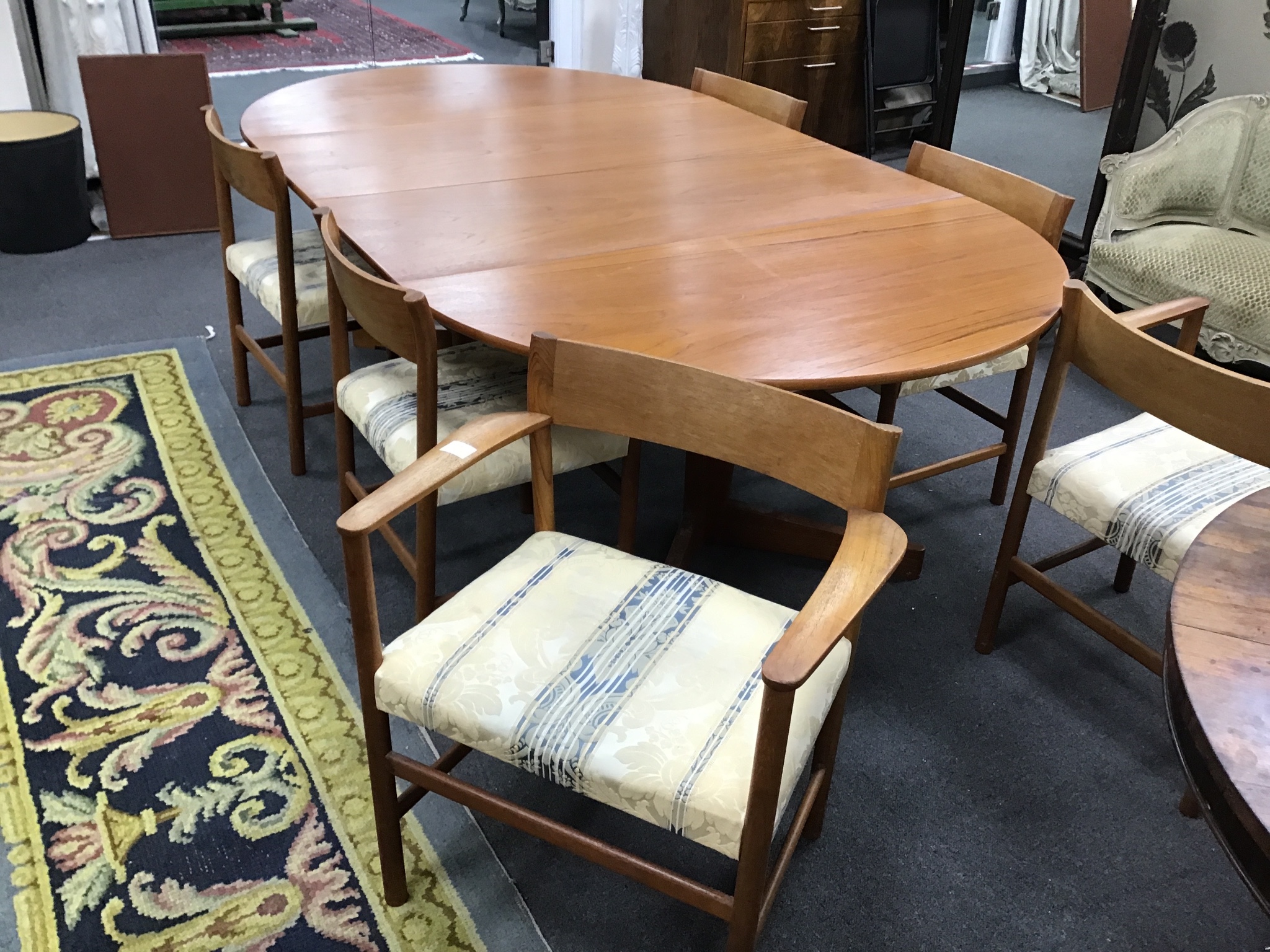 A 1950s teak Danish extending dining table and six chairs, two with arms, table extended 229cm, two spare leaves, width 129cm height 70cm